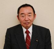 スーツを着て立っている小嶋武夫議員の写真