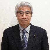 眼鏡をかけて、スーツを着て微笑んでいる鈴木一郎議員の写真