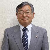 眼鏡をかけスーツを着て微笑んでいる滝沢繁議員の写真