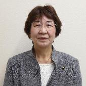 眼鏡をかけて微笑んでいる富井春美議員の写真