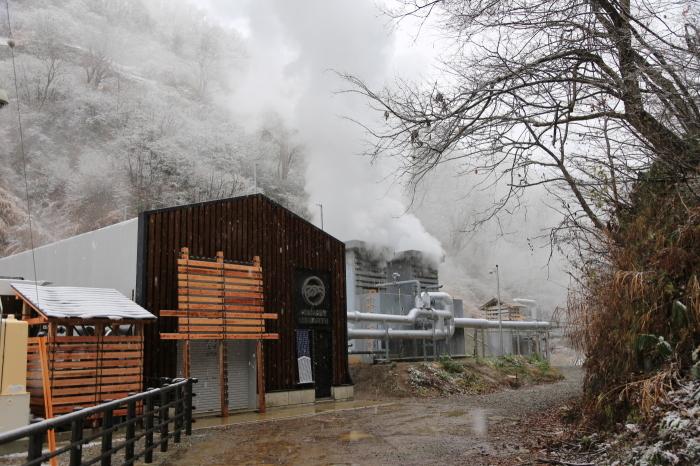 雪山の中で白い煙が沸き立っている発電所の外観写真