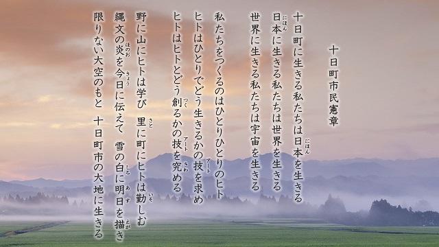 霧に霞んだ風景写真に市民憲章全文が縦書きに書かれている画像