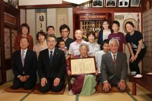 百寿の表敬訪問にて、野上女史およびその家族と記念撮影に応じる市長と地域振興局長の写真