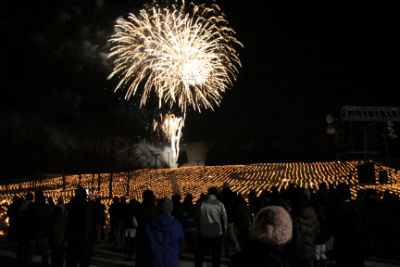 雪原に並べられたキャンドルの数々の上に打ちあがる花火。