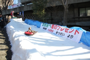 子供が雪の滑り台を滑っている。