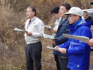 関口市長と関係者たちが書類を見ながら現地視察をしている。