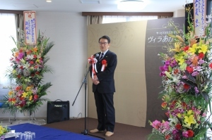 花が飾られた壇上に関口市長が立っている。