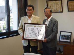 市長室にて新潟県知事から送られた感謝状を持って写真撮影している市長と南魚沼地域振興局の小幡局長