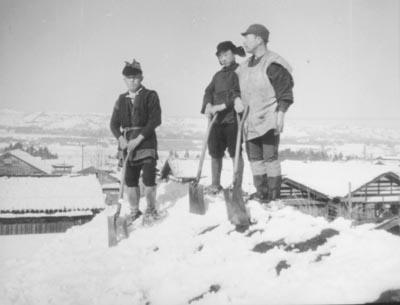昔の除雪・雪おろしをしている木製のスコップ「こしき」を持った3人の男性の当時の写真