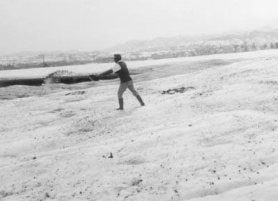 降り積もった雪に土や灰をまいて溶かしている人の写真