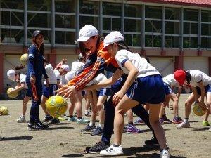 アルビレックス新潟レディースによるホームタウン活動の活動風景の写真。選手と児童がサッカーボールを用いて交流している様子がうかがえる