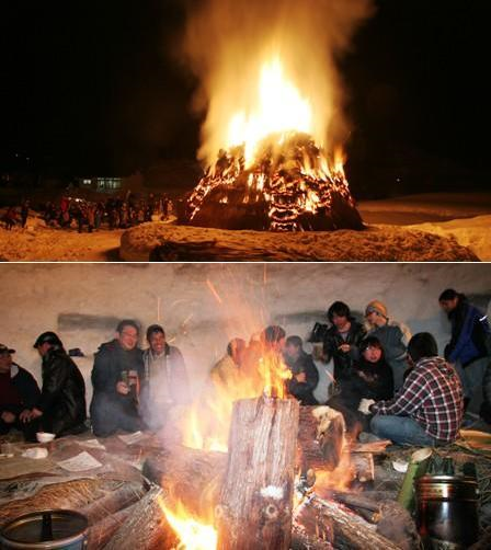 雪原上で小屋のようなものが燃えている。炎の周りに村人たちが集っている。