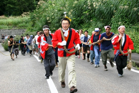 関口市長を先頭に、大勢の大人が綱を引っ張り、道路を走っている。