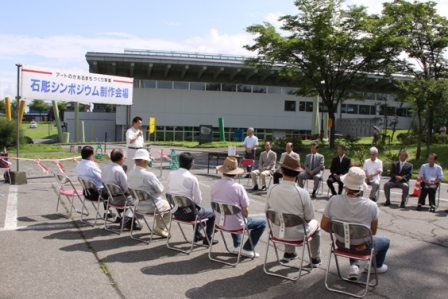 屋外で、大勢の大人たちが椅子に座って関口市長の話を聞いている。