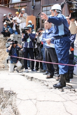 被災地を視察する仙谷官房副長官とその様子を撮影する大勢のカメラマンたち。
