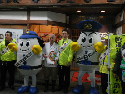 交通安全のたすきをかけてひかるくん、ひかりちゃんと一緒に飲食店を訪問する関口市長。