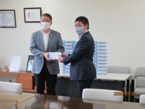 贈呈式にて福嶋理事長より手袋入りの箱を受領する市長の写真