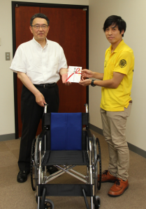 受領した車椅子と共に記念撮影に応じる市長と福納店長の写真