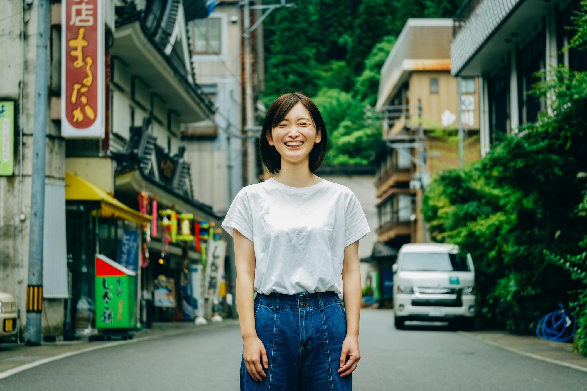 白いTシャツと青いジーンズを着ている笑顔の女性