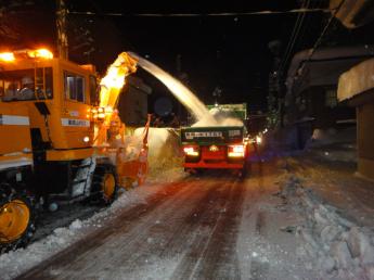 夜中に道路の除雪をしている様子の写真