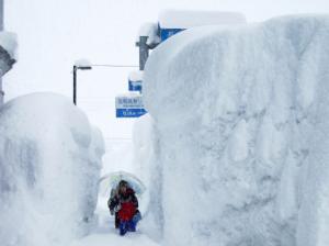 自分の背丈の倍以上ある雪と雪の間を集団登校する子供たちの写真