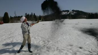 男性が雪に蓄熱効果のある木炭をまいて、雪を溶かしている様子。