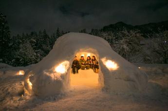 かまくらのような雪の家で過ごしている4人の様子の写真