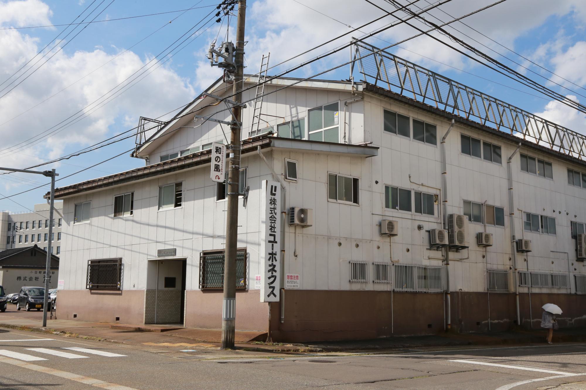 ユーボネクスと社名の入った看板がついている白い壁の工場が写っている