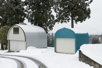雪が屋根から落ちやすいかまぼこ型の車庫の写真
