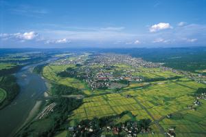 上空より俯瞰にて撮影された、信濃川と十日町市市街地の遠景の写真