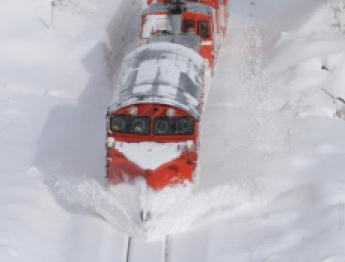 除雪しながら走行している赤い電車の写真