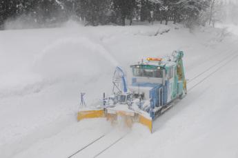 ロータリー除雪車で線路を除雪している写真