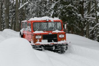 雪の上を走る赤い雪上自動車の写真