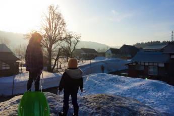 雪山から登ってくる朝日を眺めている2人の子どもの写真