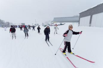 冬のグランドで小学生が授業でスキーをしている写真