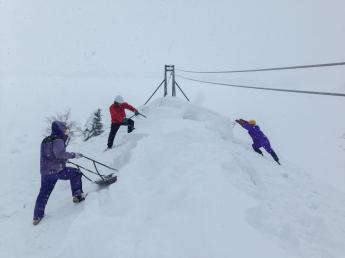 スノーダンプを巧みに操って雪を下ろしている男性3人組の様子の写真