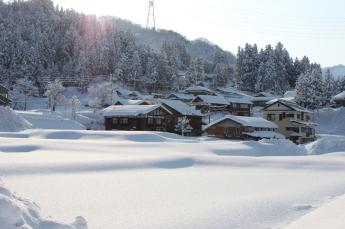 一面雪景色となった集落に、山の尾根から日が差し始めた瞬間の写真