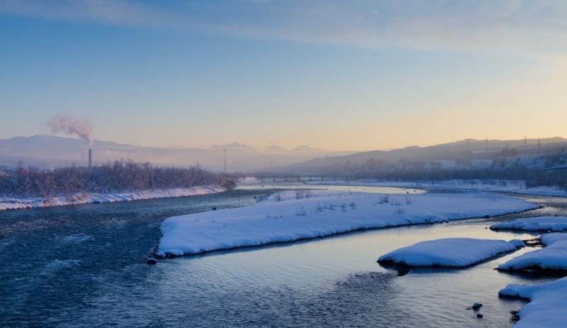 赤い色の夕日の光が射す雪が照らす川の風景写真