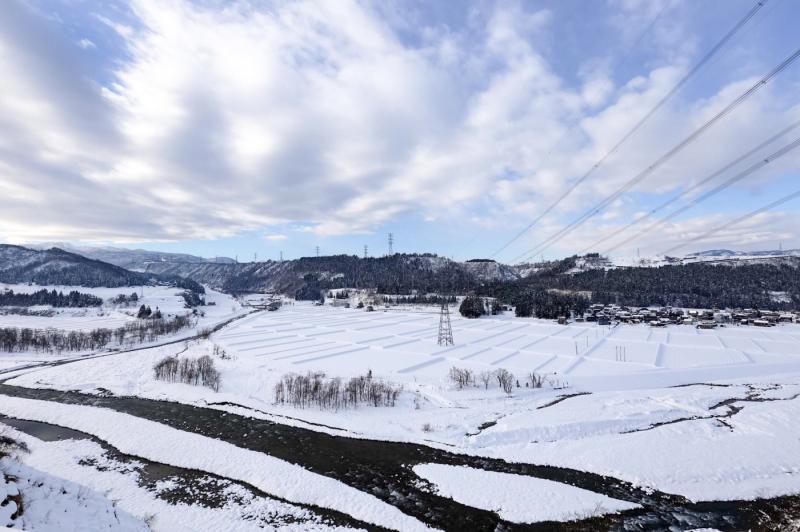 一面に雪が積もった畑と電線がはられた近くで撮影された風景写真