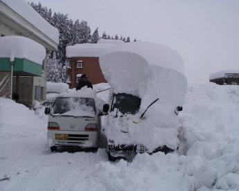 トラックの屋根の上に1m以上の雪が積もり、今にも潰れそうな様子