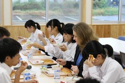テーブルを囲んで生徒たちが給食を楽しんでいる写真