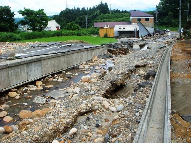 河川が氾濫し、路盤が流され、瓦礫が道路を覆っている所の写真